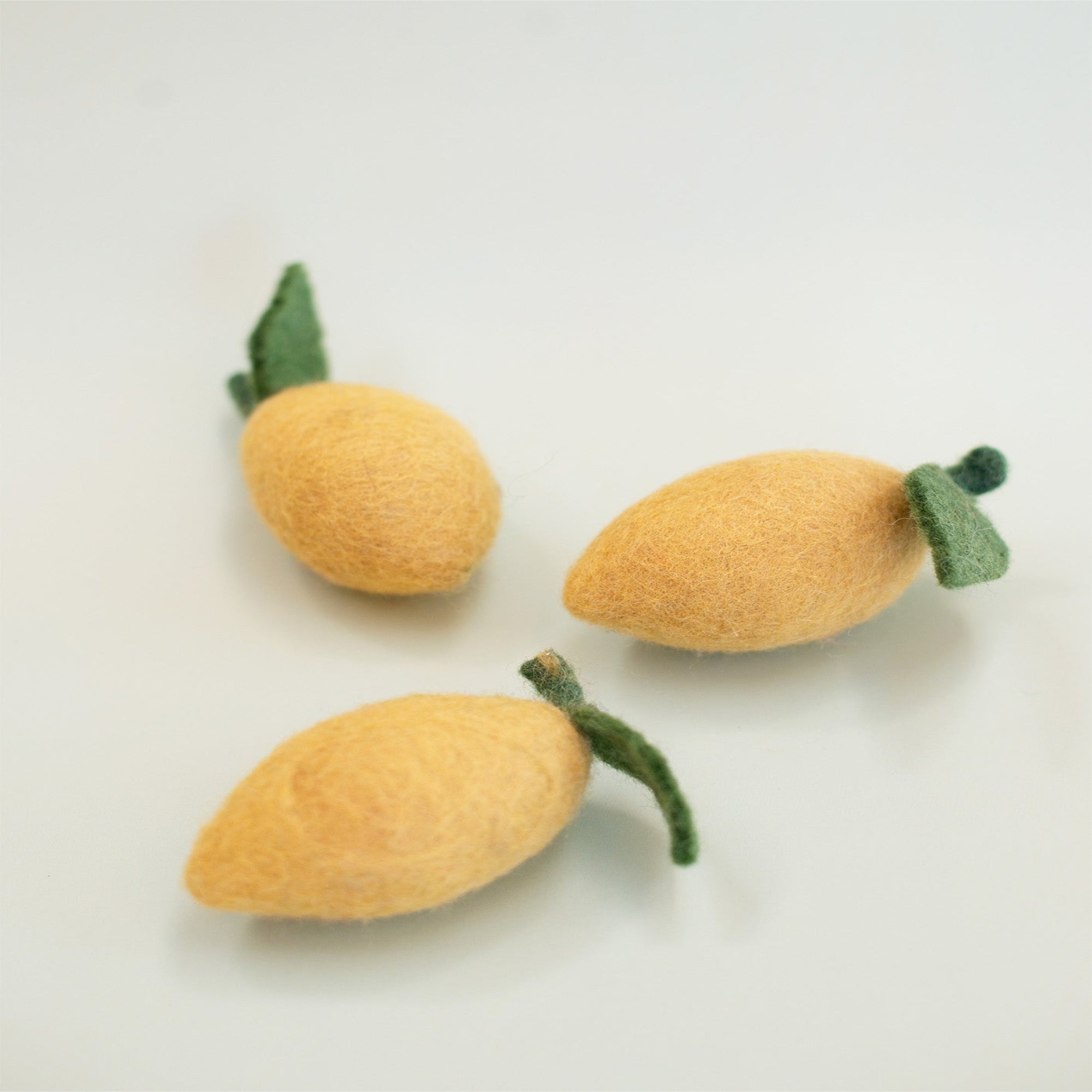 Three felt pet toy lemons on a light background