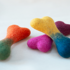 Colorful heart-shaped felt toys on a white background