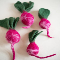 Felted radishes with green leaves on a white background