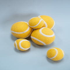 Yellow tennis balls with white strings on a light gray background