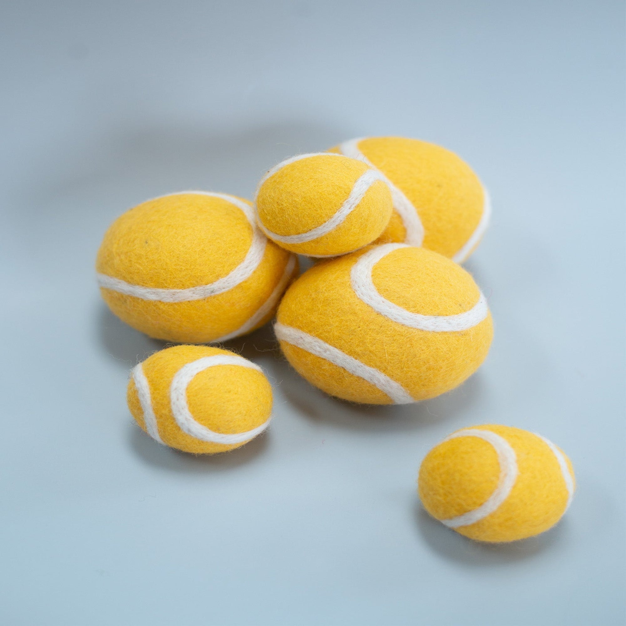 Yellow tennis balls with white strings on a light gray background